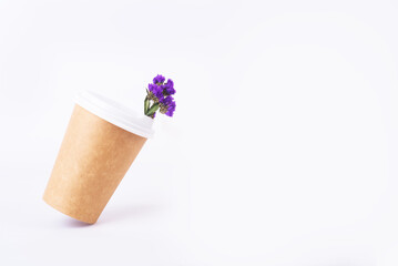 coffee cup of reusable materials with blue flowers inside at an angle to white background. zero waste concept.