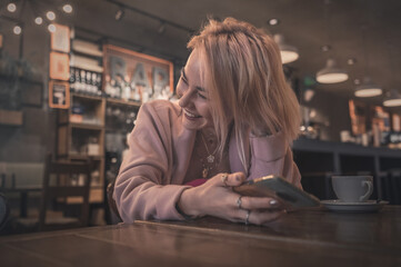 Fototapeta na wymiar Young woman using smartphone in cafe with dark lighting