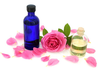 Fototapeta na wymiar Rose water in blue glass bottle with flower and rose petals on white. Can maintain the skins ph balance, helps to reduce redness of skin, can help heal acne, dermatitis, eczema and is anti bacterial.