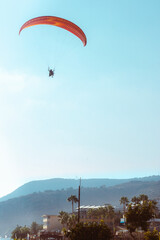 Skydiver with a red parachute. Buildings and mountain in the background