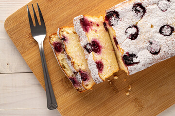 A few slices of homemade cottage cheese casserole with cherries and a fork on a bamboo board, macro, top view.


