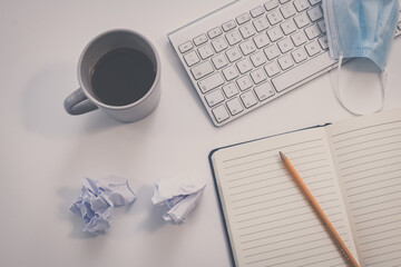 Desktop view with keyboard, pencil, agenda and books. Table with objects for smart working or homeschooling. Organization, remote work, study, creativity, production, indecision, confusion concept.