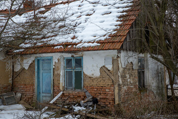 Destroyed and ruined house with red ceramic tiles, abandoned in the village