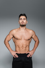 Fototapeta premium muscular sportsman standing with hands on hips isolated on grey.