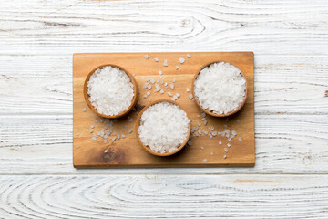 A wooden bowl of salt crystals on a wooden background. Salt in rustic bowls, top view with copy space