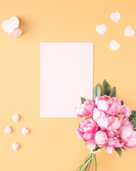 Valentine's Day.love creative arrangement of light pink hearts and flower bouquet with blank white paper against sandy pastel background. Flat lay artistic. Copy space.