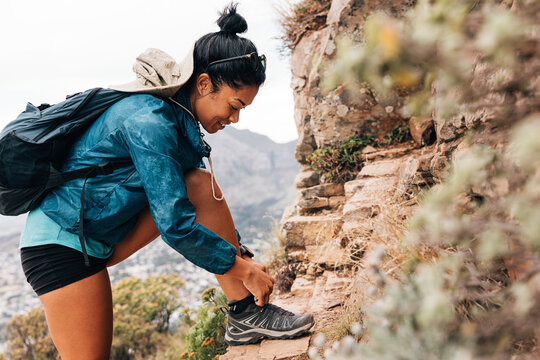 Side view of young woman tying her shoelaces during hike