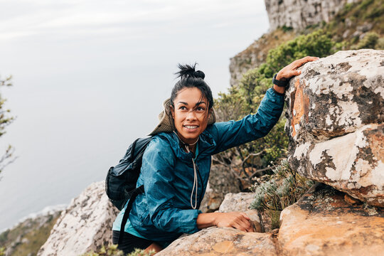 Portrait of a woman with backpack and sports clothes climbing up on a mountain