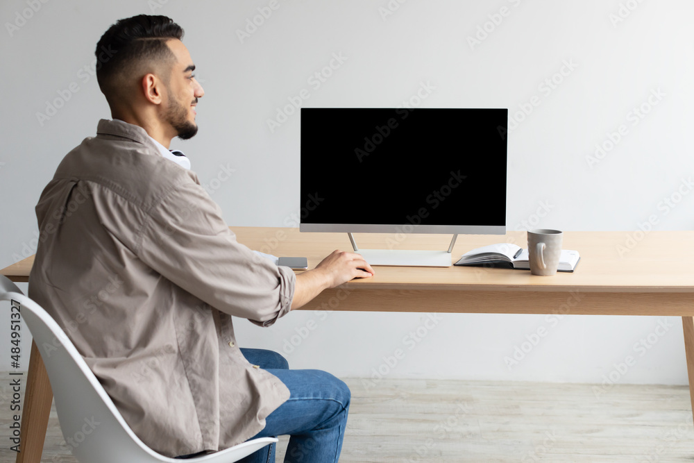 Poster arab man looking at blank empty computer monitor
