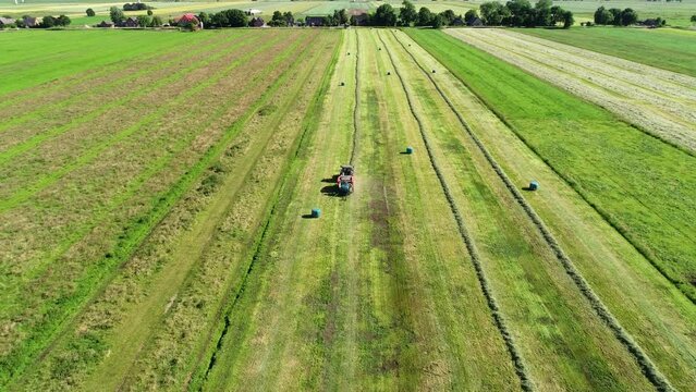 Treker mit einer Stroh Festkammerpresse bei der Strohernte auf einem gem&auml;hten Feld
