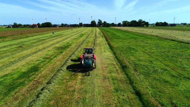Treker mit einer Stroh Festkammerpresse bei der Strohernte auf einem gem&auml;hten Feld