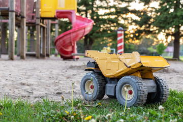 Old rusty toy truck abandoned in the park playground. Poor childhood concept.