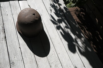 Remember the war! A rusty German helmet from World War II, pierced by a bullet, on a white table illuminated by the sun