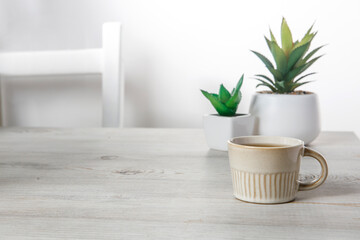 Office desk wood table of the business work place, artificial plants and coffee cup with copy space on grey wooden table.