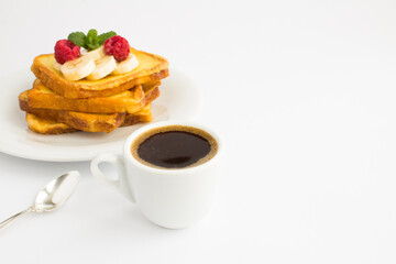 French toasts with banana, raspberry and coffee cup on the white background. Breakfast. Copy space.