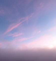 Obraz premium Sunrise creates beautiful pink colors on the clouds above the grey morning fog.