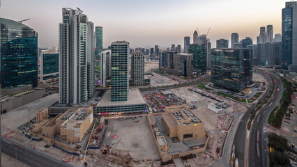 Business Bay Dubai skyscrapers with water canal aerial day to night timelapse.