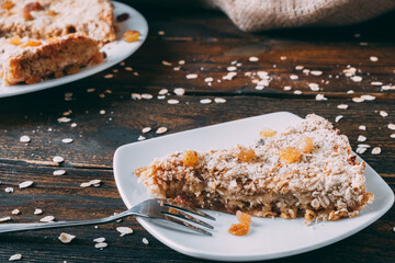 Piece of apple oatmeal pie on white plate. Delicious healthy pastry without sugar with raisins.