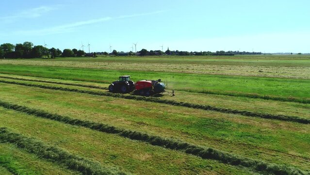 Treker mit einer Stroh Festkammerpresse bei der Strohernte auf einem gem&auml;hten Feld
