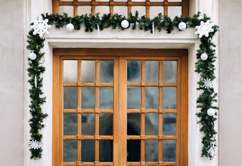 Fototapeta na wymiar Wooden brown window decorated with Christmas branches of spruce with cones and toys. The concept of festive decor in the exterior.