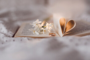 Wedding golden ring and open book with folded sheets in heart shape. Wedding concept, Valentines Day