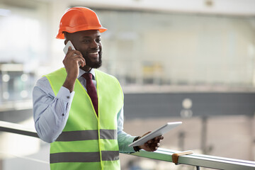 African american architect having phone conversation, using pad