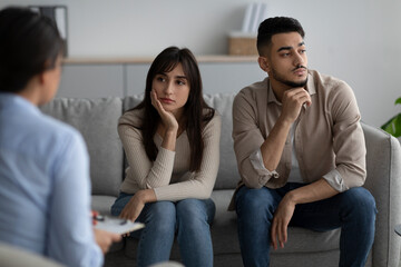 Relationship crisis and misunderstanding. Offended arab spouses sitting separate on couch at marriage therapy session