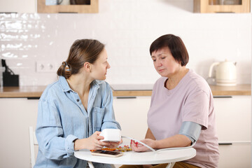 young woman checking blood pressure measurement for the senior mother at home during the Covid-19 outbreak, elderly people check health using a blood pressure monitor,health care,stay home