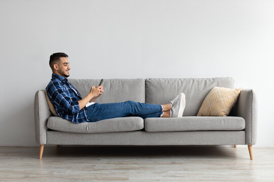 Portrait of smiling Arab man using smartphone at home