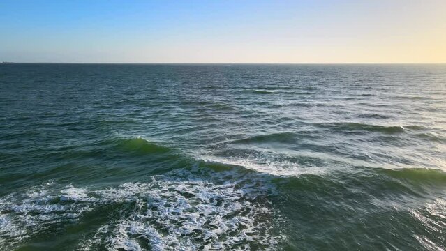 Zoom In on Ocean with Blue, Orange Sky Horizon in Background