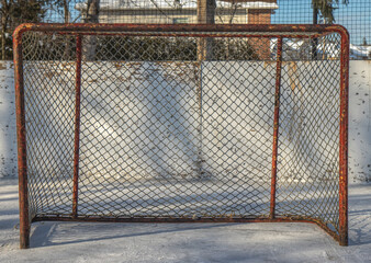 Empty hockey goal net on an outdoor rink, rink boards in back, nobody