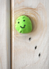 small pea sewn from fabric smiles on a wooden background