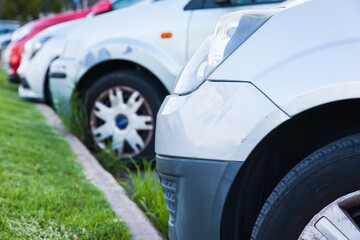 Cars are standing at the side of the road, with a green lawn, parked, close-up, side view.