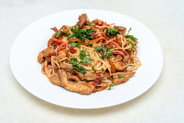 Rice noodles with meat and vegetables garnished with parsley.