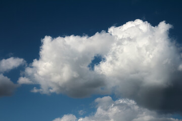 Fototapeta na wymiar White, little stormy cloud on dark blue sky; color photo.