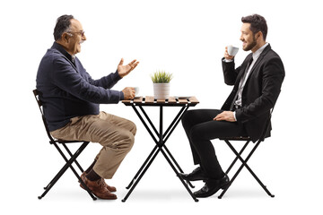 Businessman and a mature man sitting at a cafe table and having coffee