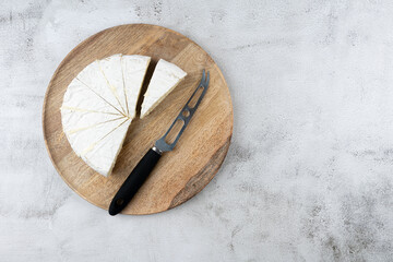 Cheese knife and sliced round white cheese - a traditional dairy creamy dairy product on a wooden board plate. HOME, Country style.