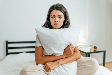 Young woman sitting on the bed looking sad