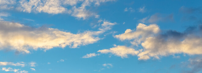 Obraz premium Golden clouds in the blue sky illuminated by the evening sun
