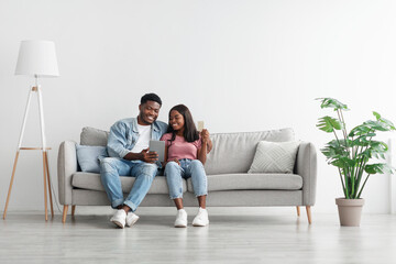 Black couple using pc and debit credit card at home