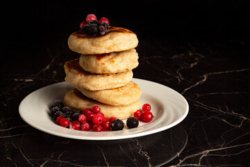 berries with pancakes in a stack on a white plate