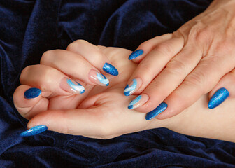 Female hands with a multicolored manicure on dark blue background closeup