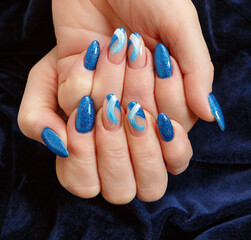 Female hands with a multicolored manicure on dark blue background closeup