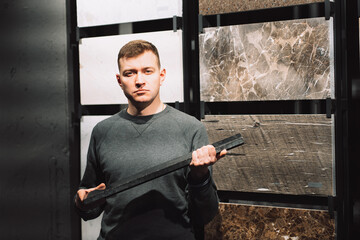 a man in the granite tile department holds a large piece of granite sample in his hands,...