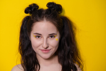 portrait of attractive brunette woman with little heart on face on yellow background. portrait of beautiful girl on colorful background.