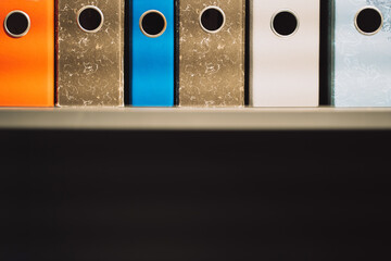 folders of different colors and shapes for documents and papers on a shelf