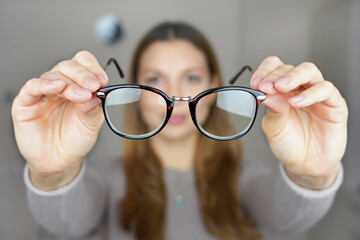 Poor eyesight concept. Girl holds glasses for sight in her hands.