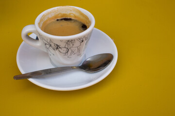 Cup of coffee on a yellow table. Breakfast concept.