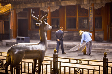 Two workers and a deer statue in The enchanting Forbidden City in Beijing in the morning sunlight. Beijing, China