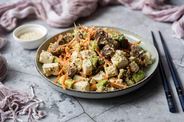 Korean dish: Salad with Korean carrots, olives and feta on a beautiful plate on a gray background. Close-up